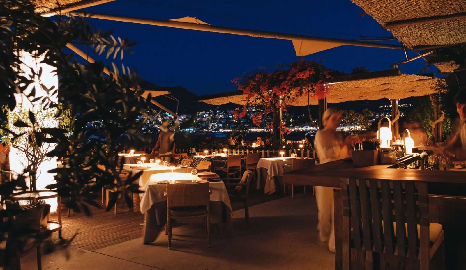 Maçakizi · Bodrum, la terrasse à la nuit tombée, la baie éclairée · Photographie fournie